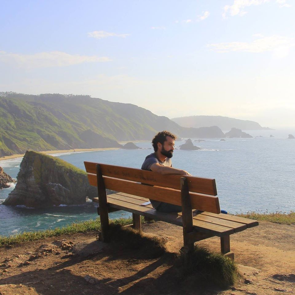 Foto en la que Valentín está sentado en un banco mirando al mar